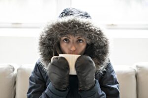 woman-wearing-parka-and-drinking-out-of-mug-inside-home